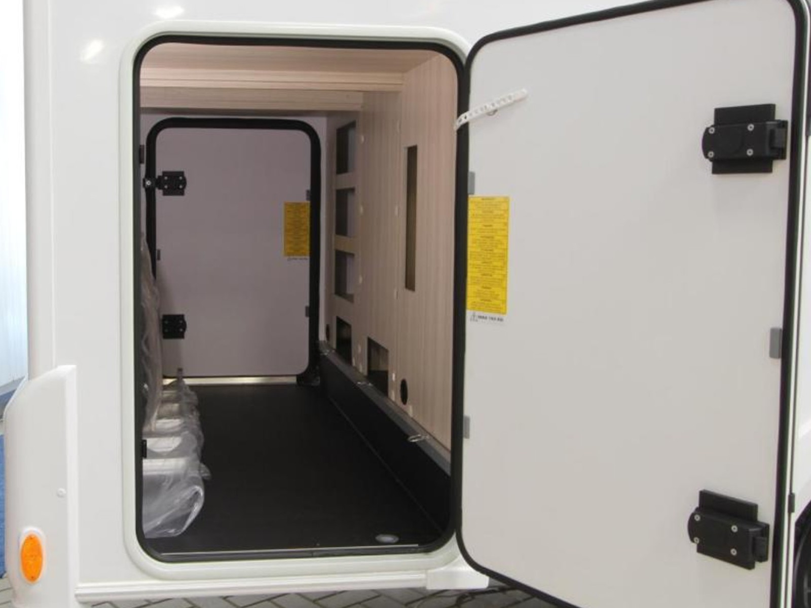 Ruime garage van de Sun Living S72DL camper, met open deur en veel opbergruimte voor bagage en uitrusting.